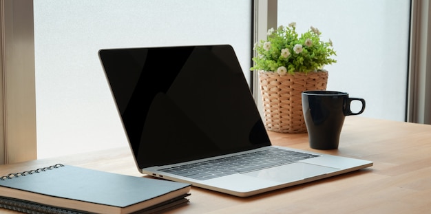 Öffnen Sie Laptop-Computer mit Büroartikel auf Holztisch