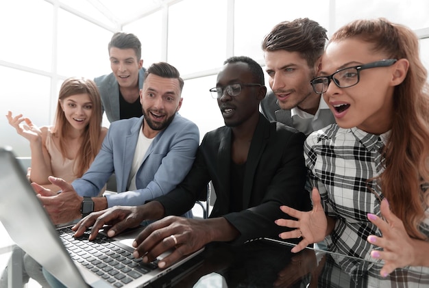 Foto Ökonomen, die auf den bildschirm eines laptop-computers schauen, mit staunenden ausdrucksgefühlen im modernen büro