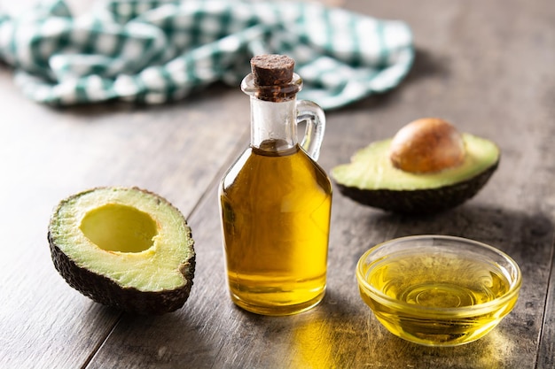 Öl und reife frische avocado auf rustikalem holztisch