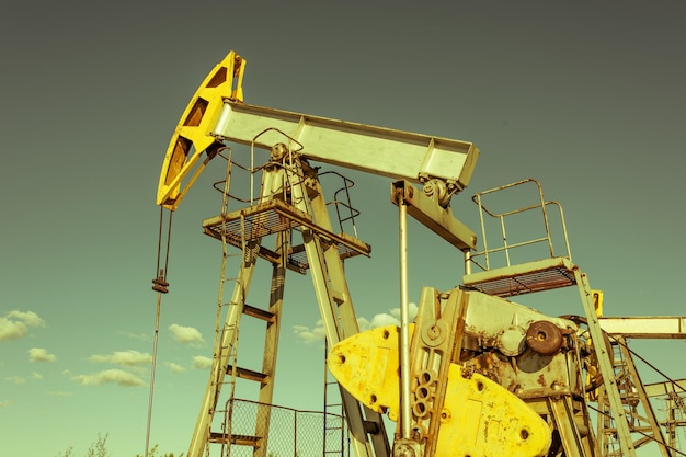 Ölpumpen-Rig Betrieb auf der Plattform in der Öl- und Gasindustrie. Pumpjack, Industrieanlagen. Ölfeldbaustelle, Ölpumpe läuft. Schaukelmaschinen zur Stromerzeugung. Erdöl-Konzept. Getönt.