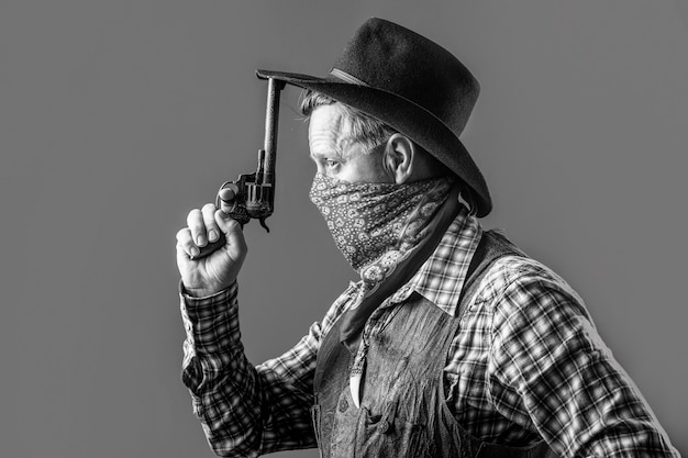 Oeste, armas. Retrato de un vaquero. Bandido americano en máscara, hombre occidental con sombrero. Retrato de vaquero con sombrero. Retrato de hombre con sombrero de vaquero, pistola. Retrato de un vaquero. En blanco y negro.