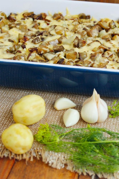 Ofenkartoffel mit Scheiben Auberginenkäse und Knoblauch. Neue Kartoffeln, Knoblauch und Fenchel auf dem Tisch