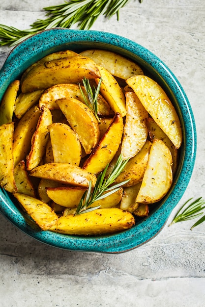 Ofenkartoffel zwängt mit Rosmarin im blauen Teller, Draufsicht. Gesundes veganes Lebensmittelkonzept.