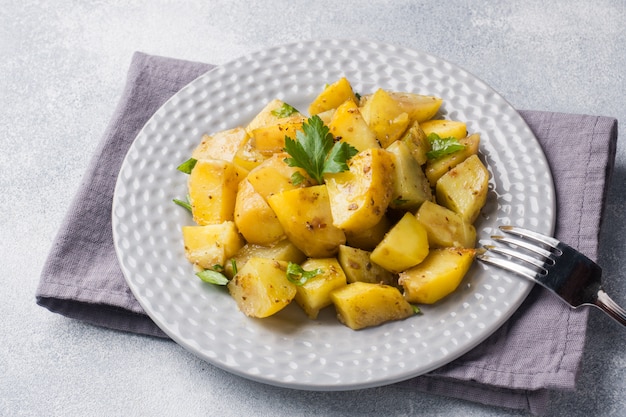 Ofenkartoffeln mit Gewürzen und Kräutern auf einer Platte.