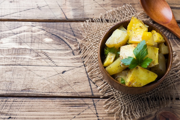 Ofenkartoffeln mit Gewürzen und Kräutern in der hölzernen Platte. Platz kopieren