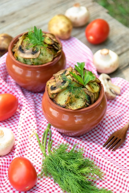 Ofenkartoffeln mit Pilzen und Fleisch in einem Tontopf.