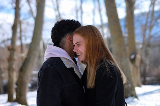 Oferta de una feliz pareja interracial joven disfrutando juntos de un día de invierno cubierto de nieve