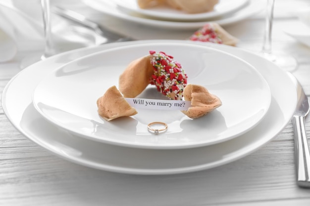 Oferta de matrimonio con galletas de la fortuna y anillo en primer plano de placa blanca