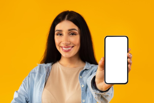 Foto oferta móvil mujer embarazada feliz mostrando teléfono celular con pantalla blanca en blanco y maqueta de enfoque selectivo sonriente