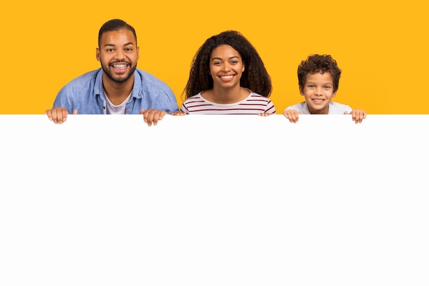 Oferta para famílias, pais negros e filho apoiados em quadro de propaganda branco