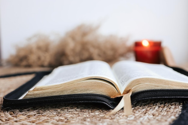 Offene Bibel auf einem alten Holztisch und weißem Wandhintergrund Religionskonzept Gemütliches warmes Foto