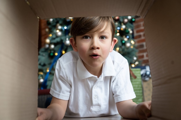 Offene Geschenkbox des kleinen Jungen mit Freude und Glück. Weihnachtsbaum