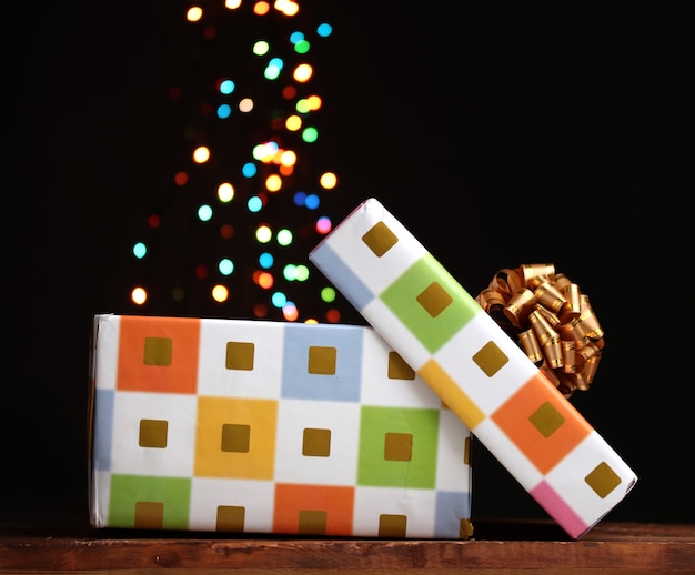 Offene Geschenkbox mit Bokeh-Hintergrund auf Schwarz