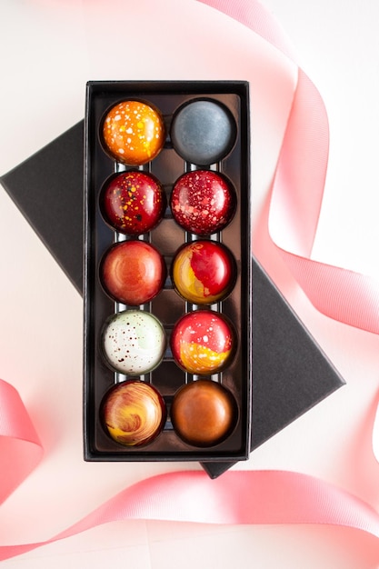 Offene Geschenkbox mit einer Auswahl an hausgemachten Schokoladenbonbons Moderne handbemalte Schokoladenbonbons Produktkonzept für Chocolatier