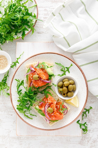 Offene Sandwiches mit gesalzenen Lachs-Avocado-Oliven und Rucola Frühstück Draufsicht