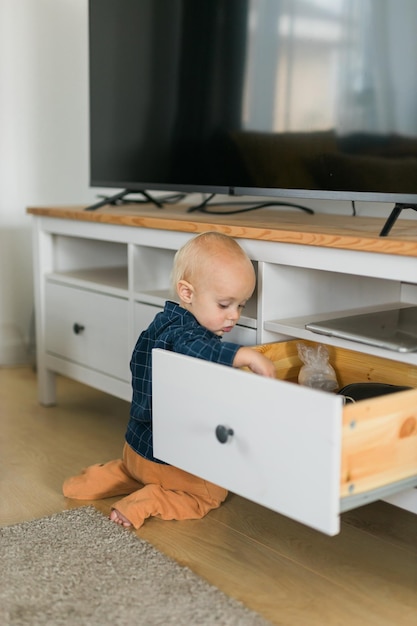 Offene Schrankschublade des Kleinkindbabyjungen mit seinem Handkind erforschen, was im Schrankbabyneugierde a ist