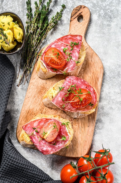 Offenes Baguette-Sandwich mit Salami-Salchichon, Kirschtomaten und Mikrogrün. grauer Hintergrund. Draufsicht