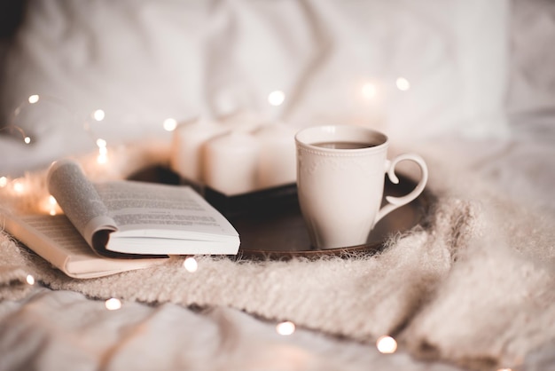 Offenes Buch mit einer Tasse Tee nachts im Bett aus nächster Nähe Gemütliche Atmosphäre