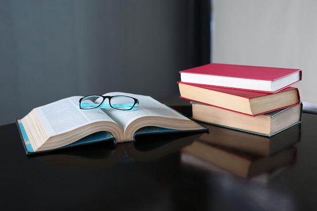 Offenes Buch und gebundene Bücher auf Holztisch in der Bibliothek.