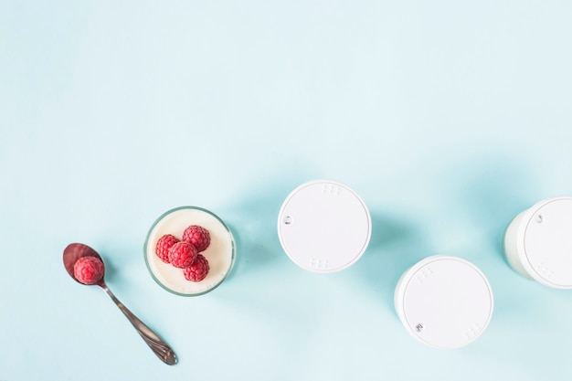 Offenes Glas mit hausgemachtem Joghurt und Himbeeren neben geschlossenen Gläsern