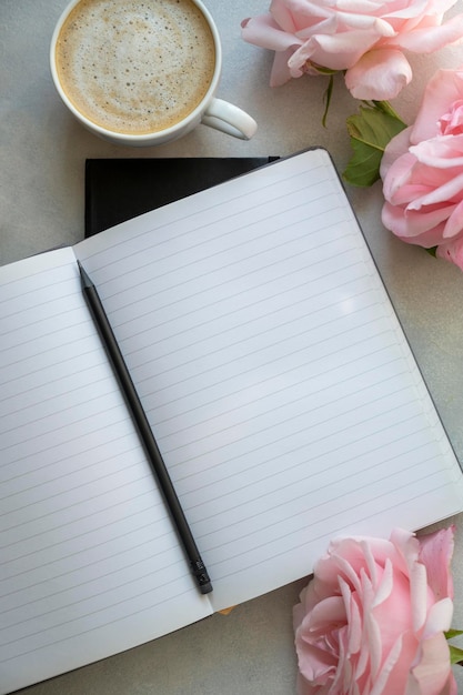 Offenes Notizbuch mit leerer Seite Mockup Tasse Kaffee rosa Rosen Blumen auf hellem Hintergrund Planen und Arbeiten auf der Tischplatte