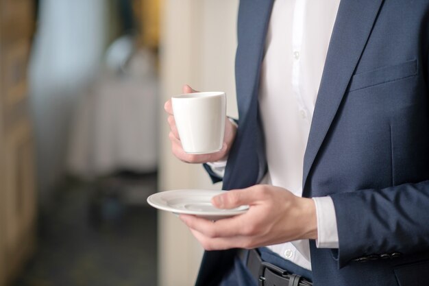 Offiziell gekleideter Mann mit einer Tasse Kaffee