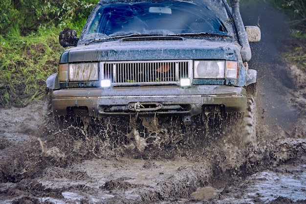 Offroader azul que participa en una carrera todoterreno en lodo de agua