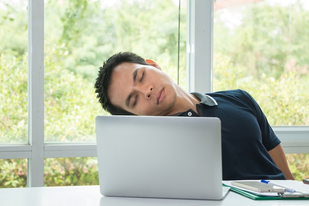 Oficial está dormindo no espaço de trabalho com laptop