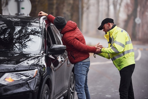 Oficial de policía con uniforme verde atrapado por robo de automóvil en la carretera.