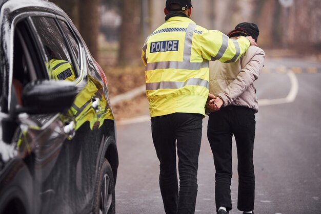 Oficial de policía con uniforme verde atrapado por robo de automóvil en la carretera.