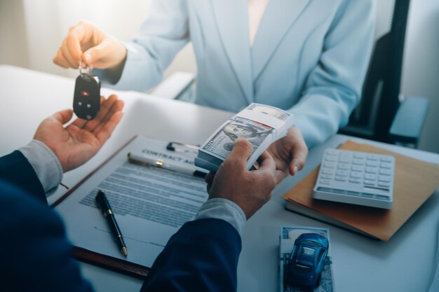 Los oficiales de seguros entregan las llaves del coche después de que el inquilino haya firmado un documento de seguro de automóvil o un documento de arrendamiento o acuerdo Comprar o vender un coche nuevo o usado con un coche