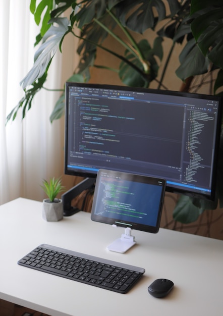 Foto oficina en casa acogedora para desarrollador. pantalla y tableta con código. trabajo de confort en casa