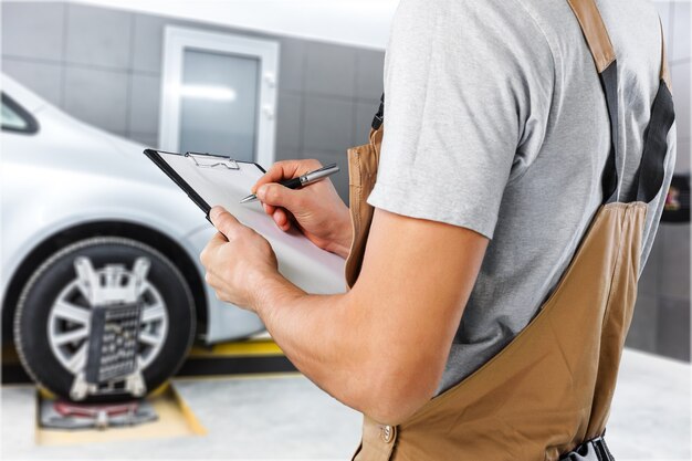 Oficina de conserto de automóveis, mecânico masculino perto do carro