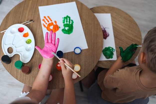 Foto oficina de desenho infantil crianças felizes fazem marcas de mãos com tinta