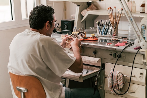 Oficina de técnico de prótese dentária com mesa cheia de ferramentas para trabalhar