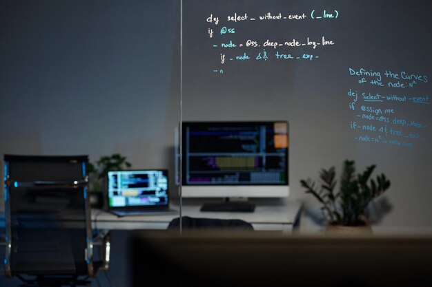 Oficina moderna con computadora y código en tablero de vidrio