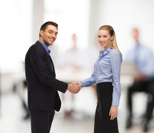 oficina, negocios, concepto de trabajo en equipo - hombre y mujer dándose la mano