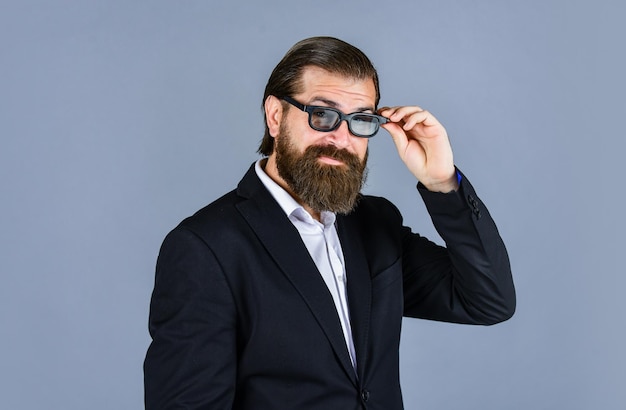 Oficina oficial estilo de vida alegre barbudo hombre guapo y exitoso en traje caro Está en camisa blanca y gafas elegante hombre exitoso en traje posando traje de hombre de negocios