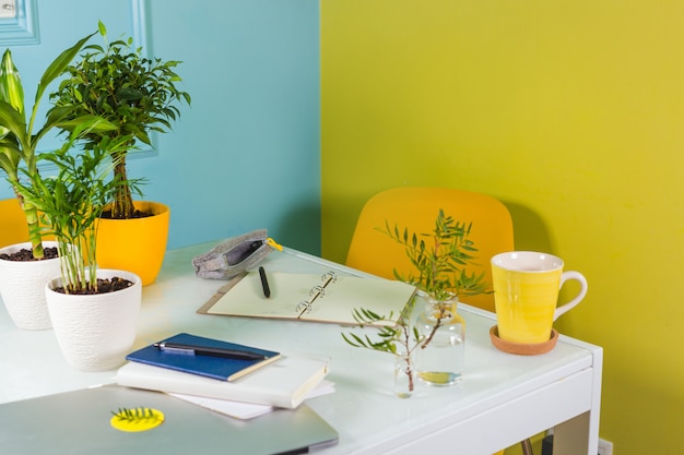 Oficina con paredes brillantes. Papelería y flores sobre la mesa