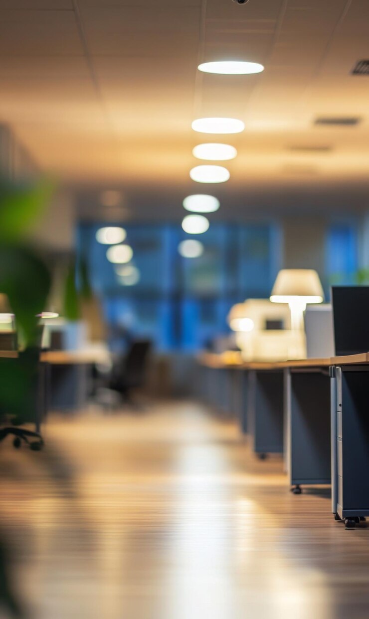 oficina de plan abierto arreglos de escritorio borrosos con colores apagados diseño contemporáneo iluminación suave de los paneles del techo espacio de copia