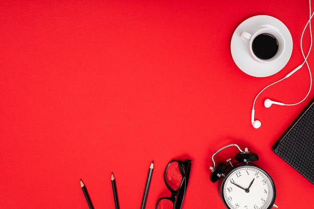 Oficina de trabajo. Relojes, gafas y lápices sobre una mesa roja