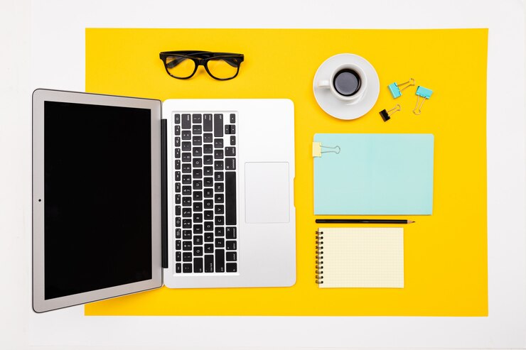 Foto oficina de trabajo. vista superior de papelería con laptop y notebooks con un diseño sobre una superficie amarilla