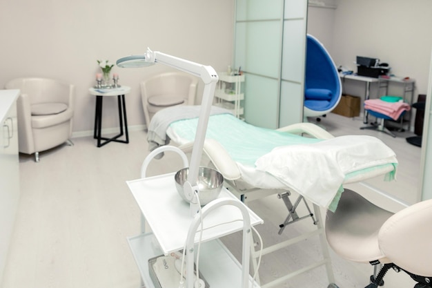 Oficina vacía de cosmetóloga con cosméticos de cuidado y mesa de masaje en un salón de belleza moderno. Interior del gabinete médico. Centro estético modernizado para el cuidado de la salud.