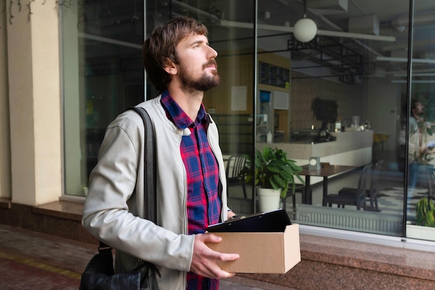 Un oficinista con una caja de cosas sale del trabajo.