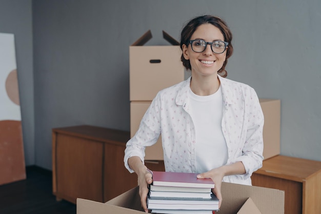 Oficinista hispana sonriente empacando cosas el día de la mudanza Nuevo concepto de reubicación de vivienda