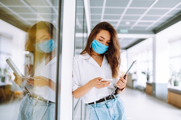 Oficinista con mascarilla trabajando en la oficina. El concepto de prevenir la propagación de la epidemia.