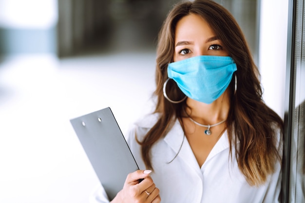 Oficinista con mascarilla trabajando en la oficina. El concepto de prevenir la propagación de la epidemia.