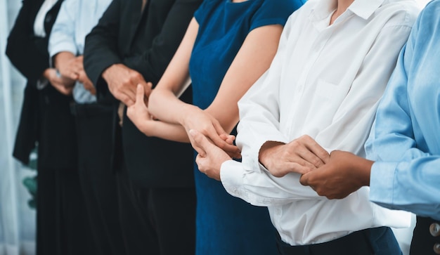 Un oficinista multirracial feliz y sonriente se toma de la mano en una línea que promueve la sinergia y la colaboración para el éxito empresarial Diversos vínculos de oficinistas profesionales en el lugar de trabajo moderno Concord