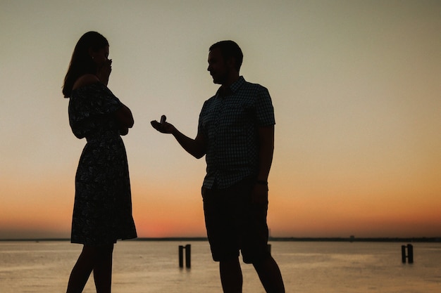 Ofrezca su mano y su corazón en la playa en el contexto de una hermosa puesta de sol, compromiso Un hombre le da un anillo y le pide a una niña que se case, ella es feliz