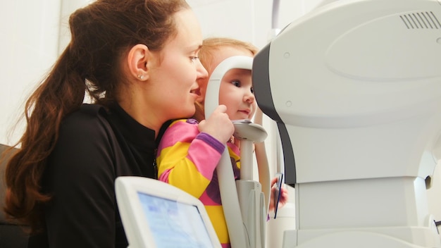 Oftalmologia infantil - optometrista verifica o olho da criança, horizontal